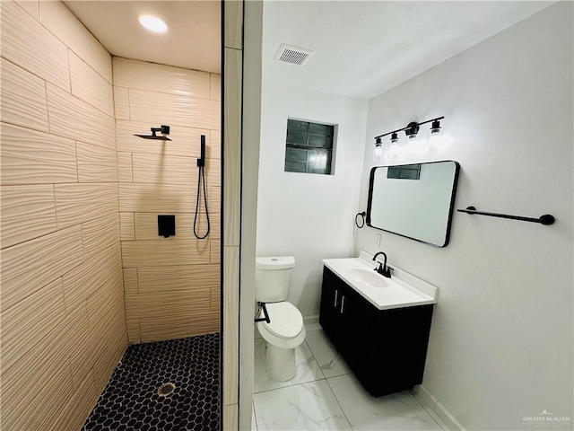 bathroom featuring vanity, a tile shower, and toilet