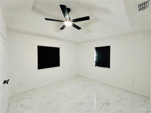 unfurnished room with ceiling fan and a raised ceiling