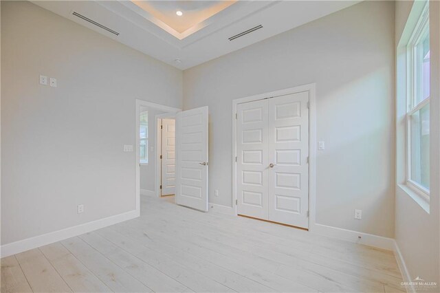 8047 N 48th Ln, Mcallen, TX 78501 - unfurnished bedroom featuring light wood-style flooring, a closet, and a raised ceiling