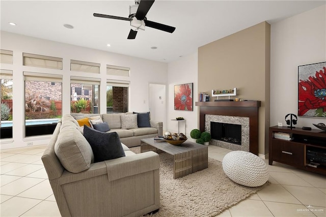 tiled living room with ceiling fan and a high end fireplace