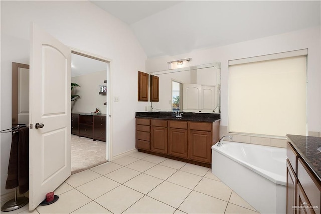 bathroom with vaulted ceiling, a tub, tile patterned floors, and vanity