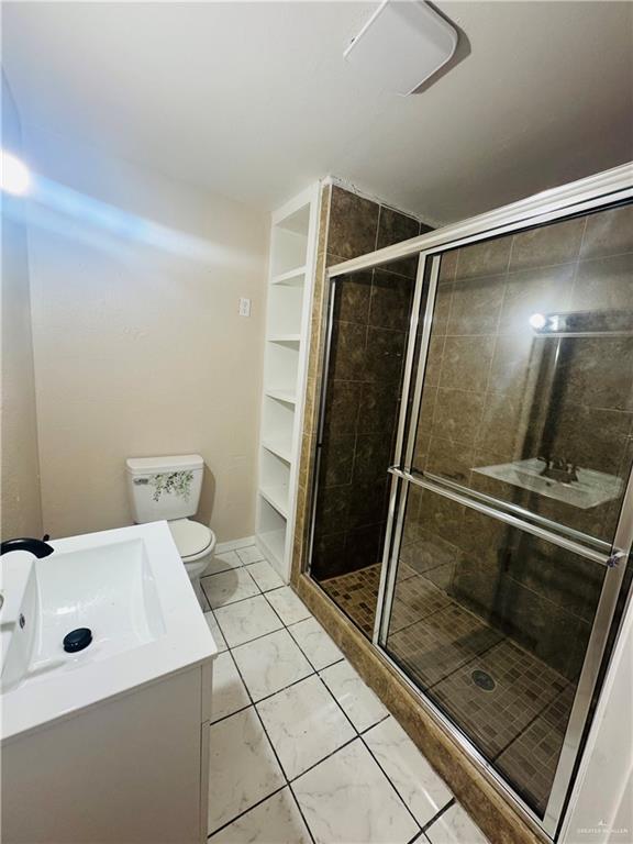 full bath featuring toilet, a shower stall, and vanity