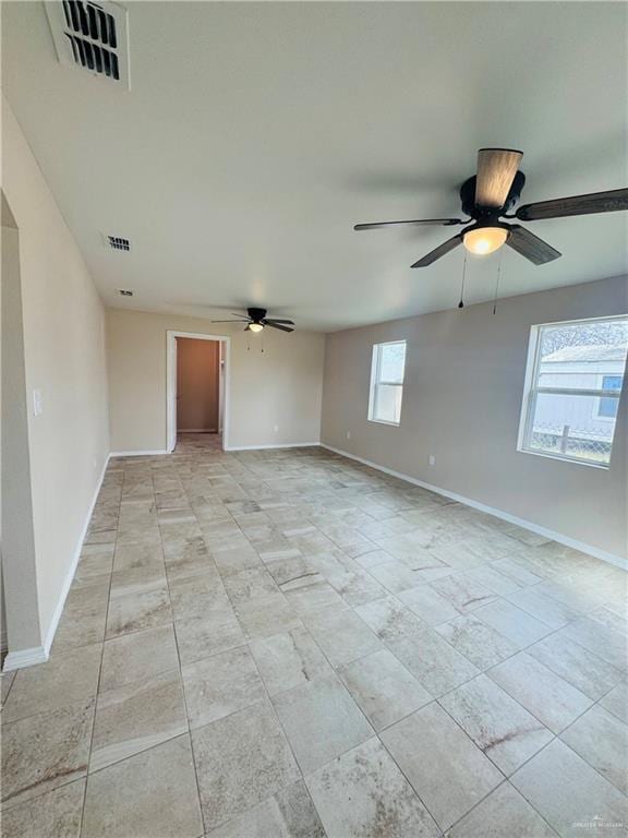 unfurnished room with ceiling fan, visible vents, and baseboards