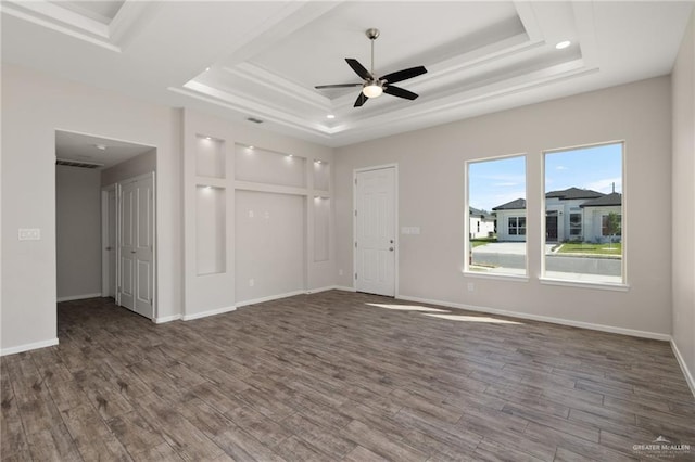 spare room with ceiling fan, a raised ceiling, and dark wood-type flooring