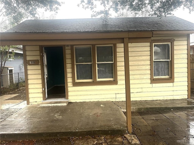 exterior space with a shingled roof and fence