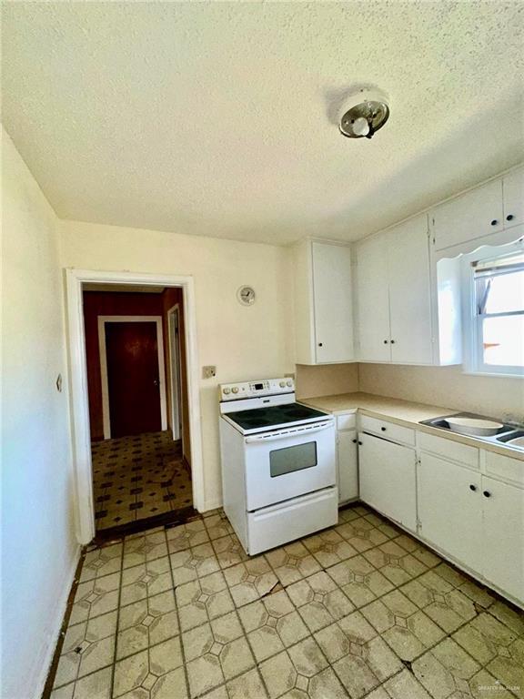 kitchen featuring sink, white electric range oven, white cabinets, and a textured ceiling