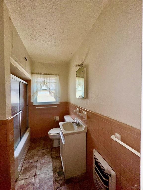 full bathroom with bathtub / shower combination, toilet, a textured ceiling, tile walls, and vanity