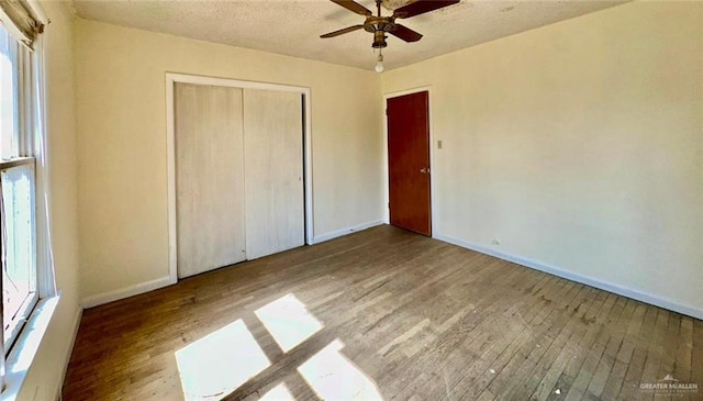 unfurnished bedroom with ceiling fan, wood-type flooring, a closet, and a textured ceiling