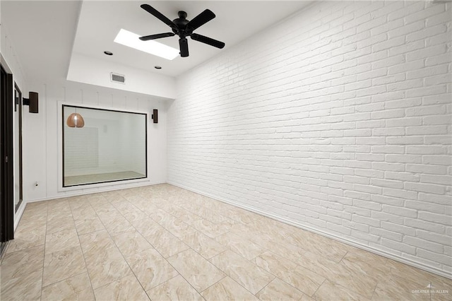 empty room with ceiling fan and brick wall