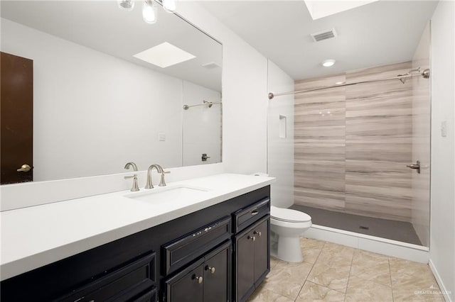 bathroom featuring vanity, toilet, tiled shower, and a skylight