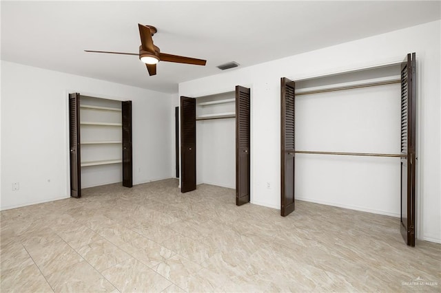 unfurnished bedroom with ceiling fan and two closets