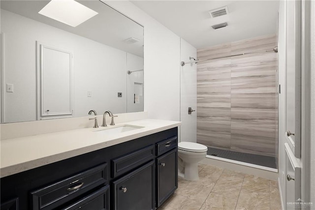 bathroom with vanity, toilet, and a tile shower