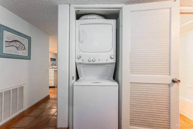 washroom featuring visible vents, laundry area, a textured ceiling, tile patterned floors, and stacked washer / dryer