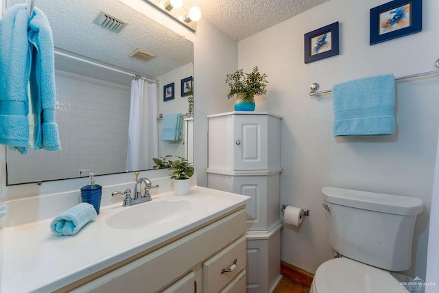 bathroom with visible vents, toilet, a textured ceiling, and vanity