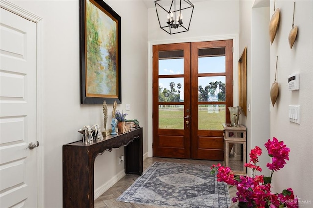 foyer with french doors, light parquet floors, and a chandelier