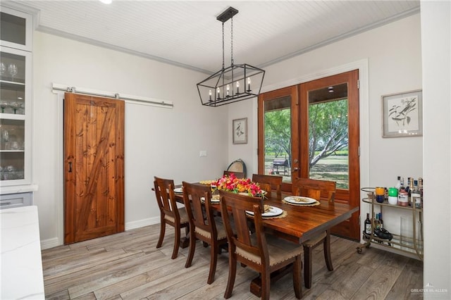 dining area featuring a barn door, light wood-type flooring, and crown molding