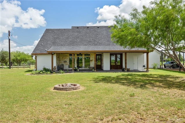 rear view of property with a fire pit, a patio area, a lawn, and french doors