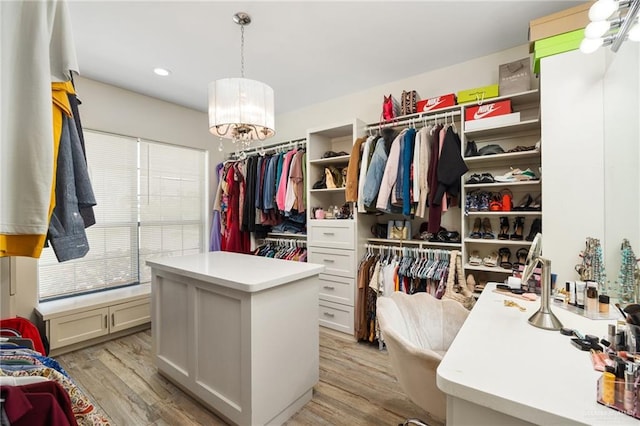 spacious closet featuring light wood-type flooring and a notable chandelier