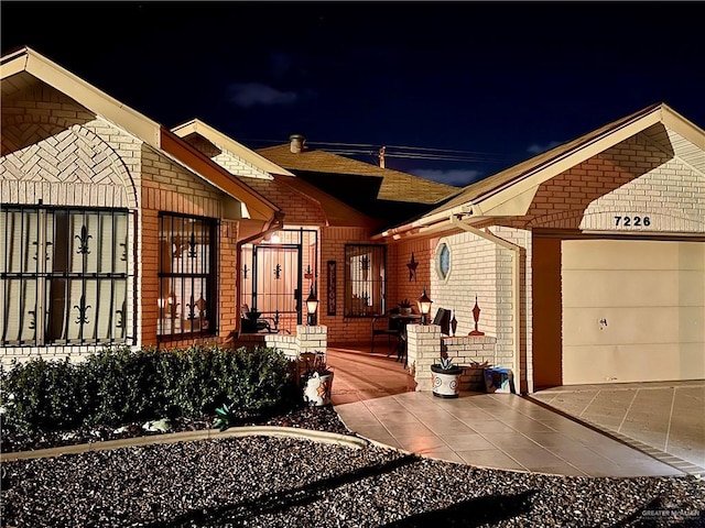 7226 Ford St, Mission, TX 78572 - exterior entry at night featuring brick siding, an attached garage, and concrete driveway