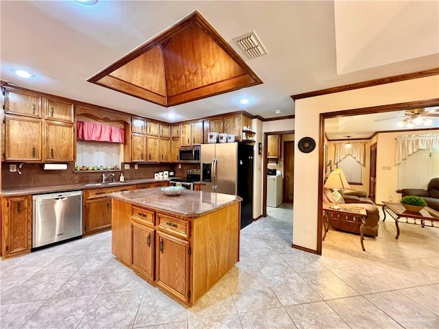 7226 Ford St, Mission, TX 78572 - kitchen with appliances with stainless steel finishes, a sink, brown cabinetry, crown molding, and a kitchen island