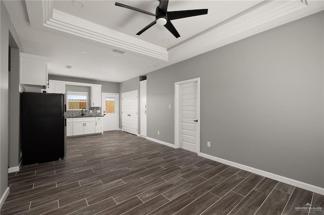 kitchen with wood tiled floor, a raised ceiling, freestanding refrigerator, and white cabinets