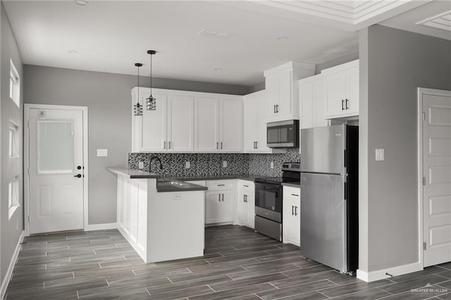 kitchen featuring decorative backsplash, white cabinets, dark countertops, hanging light fixtures, and stainless steel appliances