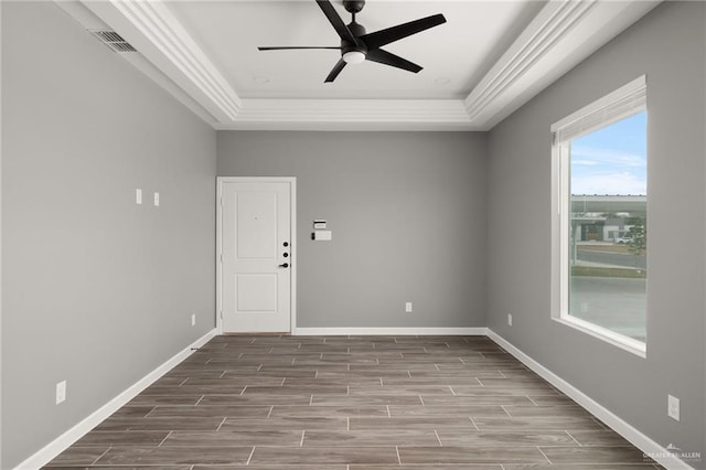 unfurnished room with wood finish floors, a raised ceiling, visible vents, and baseboards