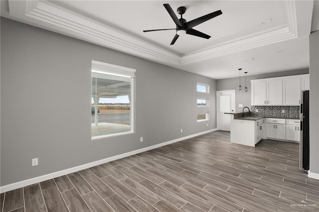 kitchen with pendant lighting, dark countertops, a raised ceiling, freestanding refrigerator, and white cabinetry