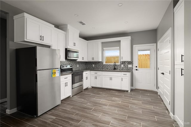 kitchen with dark countertops, visible vents, stainless steel appliances, and a sink