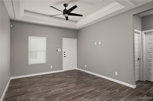 empty room with wood tiled floor, baseboards, and a raised ceiling