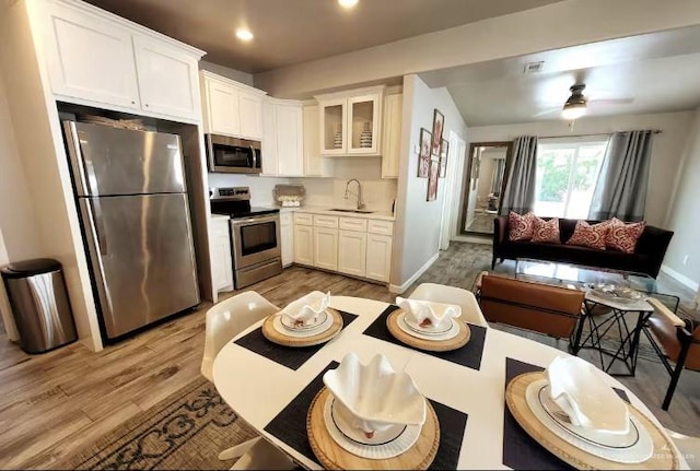 102 E Tarpon St, South Padre Island, TX 78597 - kitchen with appliances with stainless steel finishes, light wood finished floors, glass insert cabinets, white cabinetry, and recessed lighting