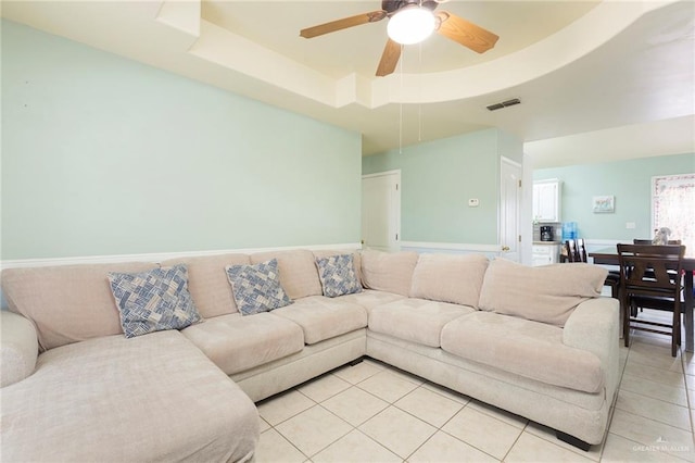 living room with ceiling fan, light tile patterned floors, and a tray ceiling