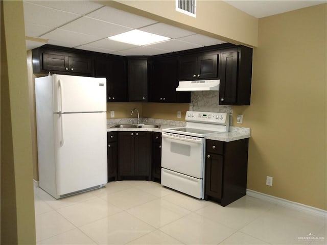 kitchen with a paneled ceiling, sink, light tile patterned floors, and white appliances