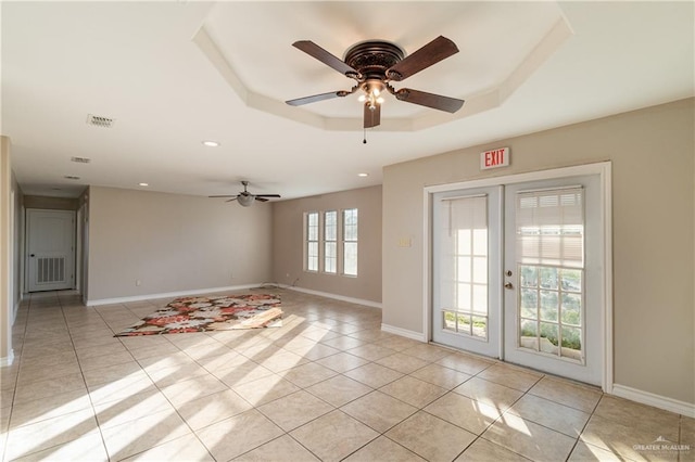 unfurnished room featuring ceiling fan, light tile patterned flooring, french doors, and a tray ceiling