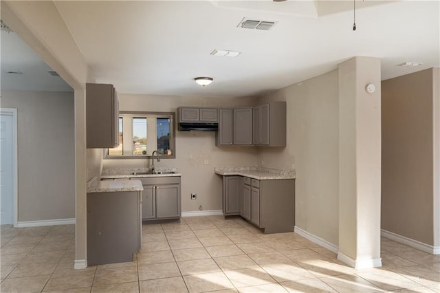 kitchen featuring light tile patterned floors, light stone countertops, sink, and gray cabinets