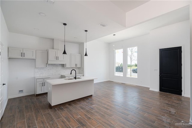 kitchen featuring sink, a center island with sink, hanging light fixtures, and dark hardwood / wood-style floors