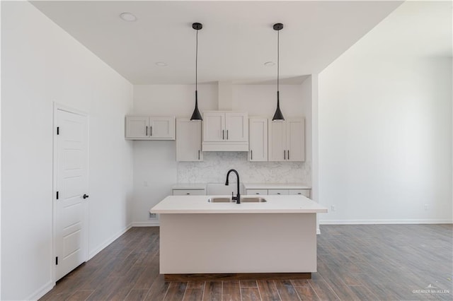 kitchen with dark hardwood / wood-style flooring, sink, a kitchen island with sink, and decorative light fixtures