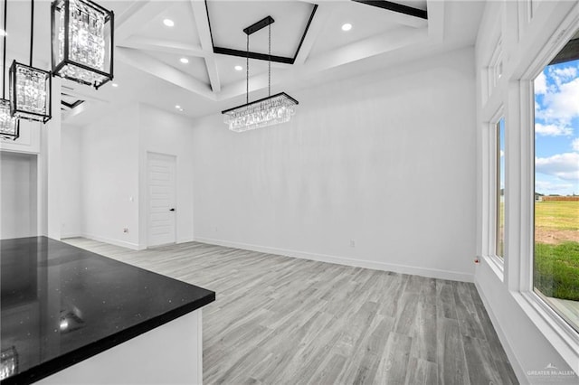 unfurnished dining area featuring coffered ceiling and light hardwood / wood-style floors