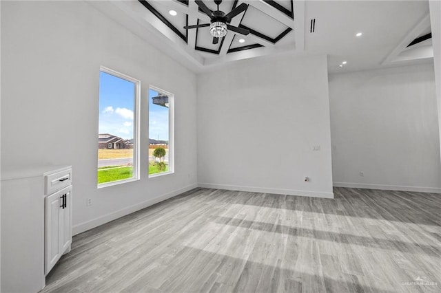 unfurnished living room featuring beamed ceiling, ceiling fan, coffered ceiling, and light hardwood / wood-style floors