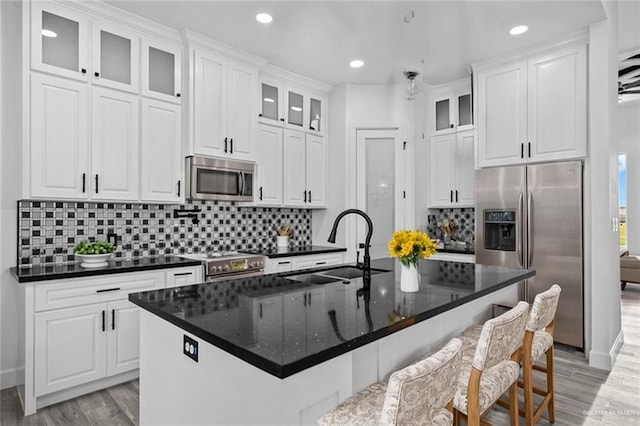 kitchen featuring stainless steel appliances, a center island with sink, white cabinets, and light hardwood / wood-style flooring