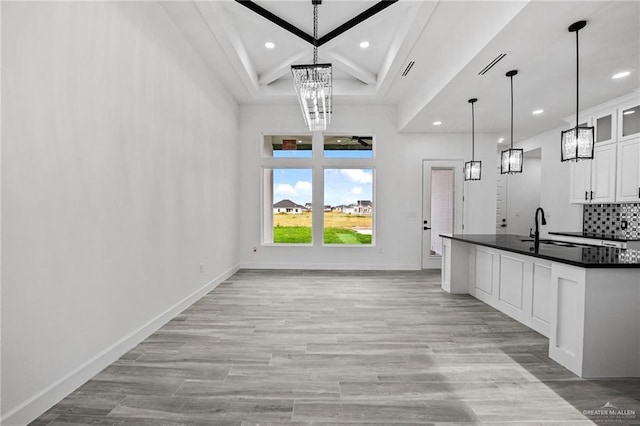 kitchen featuring sink, white cabinetry, tasteful backsplash, a notable chandelier, and decorative light fixtures