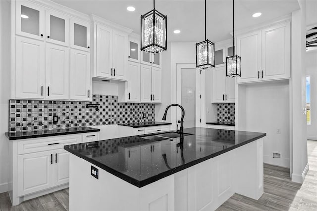 kitchen featuring pendant lighting, sink, white cabinets, a center island with sink, and light hardwood / wood-style flooring