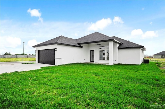 rear view of property featuring a garage, a yard, and central air condition unit