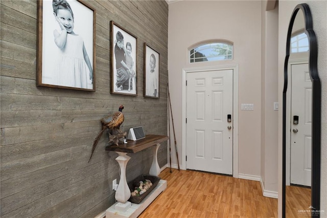 entryway featuring baseboards, wooden walls, and light wood-type flooring
