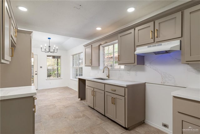 kitchen with a wealth of natural light, gray cabinetry, under cabinet range hood, and a sink