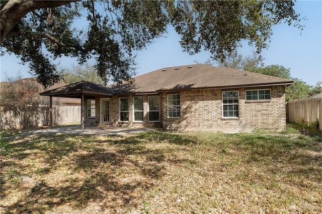 back of house with brick siding, a yard, a shingled roof, and a fenced backyard