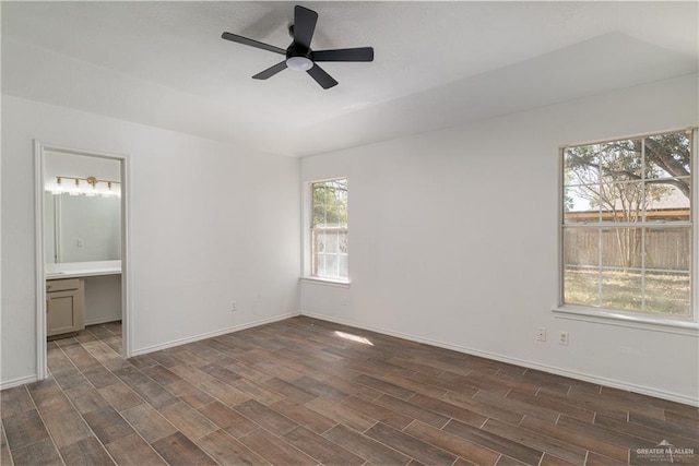 unfurnished bedroom with dark wood finished floors, ensuite bath, baseboards, and ceiling fan