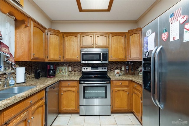 kitchen featuring light tile patterned floors, ornamental molding, appliances with stainless steel finishes, light stone countertops, and decorative backsplash