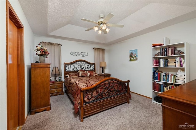 carpeted bedroom with a raised ceiling, ceiling fan, and a textured ceiling