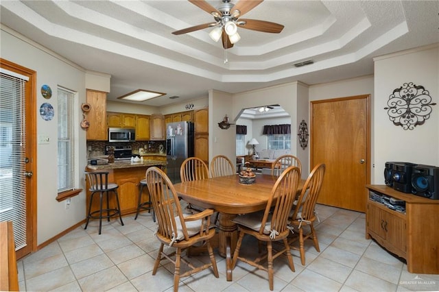 tiled dining space with a tray ceiling and ceiling fan